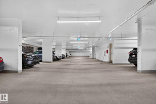 Underground parking garage featuring concrete flooring, structural columns, and overhead fluorescent lighting - 1504 9720 106 Street, Edmonton, AB 