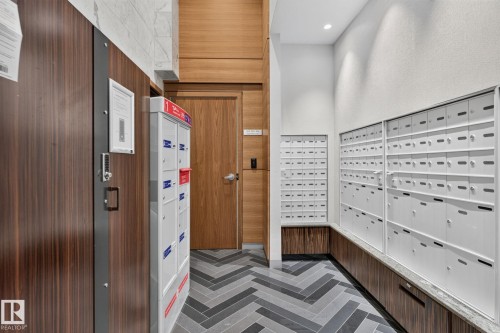 Herringbone pattern tile flooring, dark wood-finish wall panels, light wood-finish doors, and white mailboxes - 1504 9720 106 Street, Edmonton, AB 
