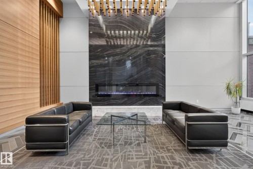 Accent wall featuring dark, veined stone surrounding an electric fireplace - 1504 9720 106 Street, Edmonton, AB 
