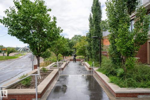 Landscaped pedestrian walkway featuring mature trees and integrated brick planters - 1504 9720 106 Street, Edmonton, AB 