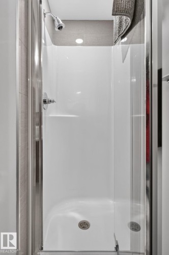 Compact shower enclosure featuring a chrome shower head and fixtures, a built-in shelf, and a clear glass door - 1504 9720 106 Street, Edmonton, AB 