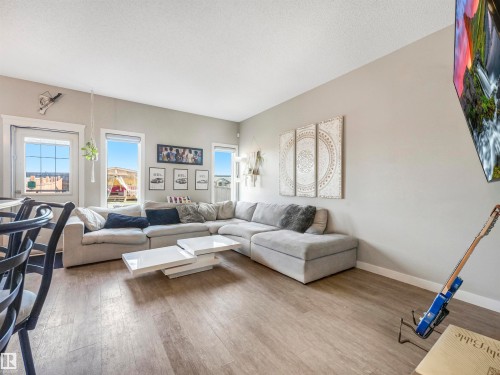 Spacious living area featuring light wood-finish flooring, light gray wall paint, and multiple large windows for abundant natural light - 17171 38 Street, Edmonton, AB 