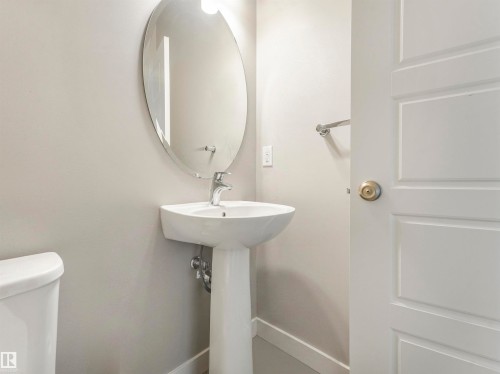 Pedestal sink with chrome faucet, complemented by an oval wall-mounted mirror - 17171 38 Street, Edmonton, AB 