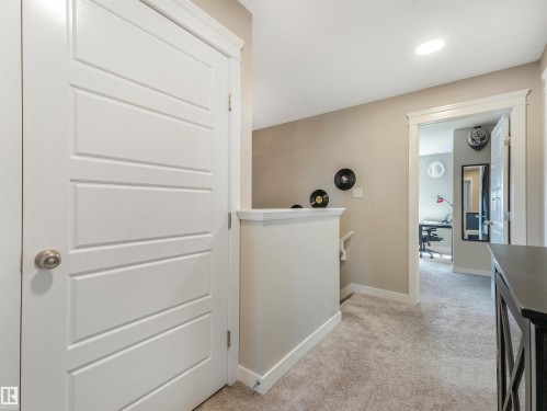 Hallway featuring light gray carpeting, neutral wall paint, white trim, recessed lighting, and a paneled door with brushed nickel hardware - 17171 38 Street, Edmonton, AB 