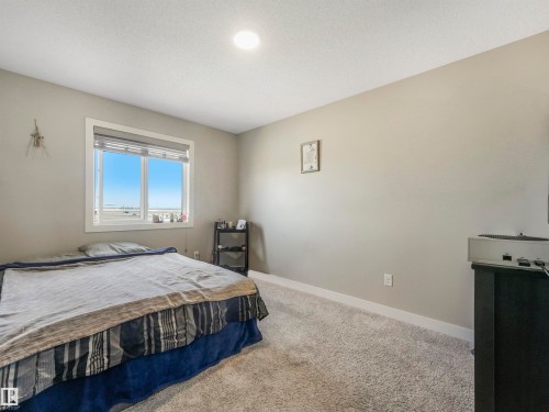 Bright room featuring a window with horizontal blinds, neutral wall paint, and light-toned carpet flooring - 17171 38 Street, Edmonton, AB 