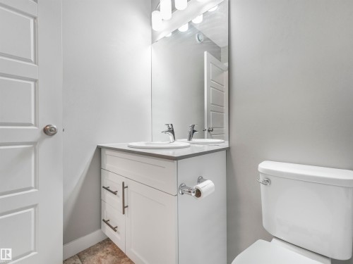 Bathroom featuring a white vanity with dark hardware, a surface-mounted sink, and a modern chrome faucet - 17171 38 Street, Edmonton, AB 