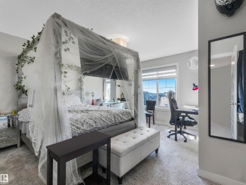 Carpeted bedroom with a large window, light gray wall paint, and a white door with black hardware - 17171 38 Street, Edmonton, AB 