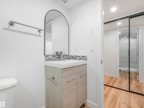 Bathroom vanity with a wood-finish cabinet, integrated sink, and mosaic tile backsplash - 17171 38 Street, Edmonton, AB 