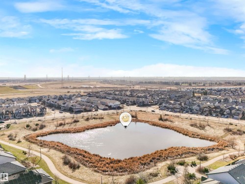 Community setting featuring a central pond with natural reed landscaping, surrounded by a paved walking path - 17171 38 Street, Edmonton, AB 