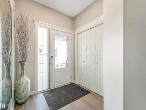 Entryway featuring a white paneled door with decorative glass, a frosted sidelight, and wood-finish flooring - 17171 38 Street, Edmonton, AB 