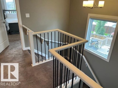 Staircase featuring white newel posts and handrails with black metal balusters - 138 Reed Place, Leduc, AB 