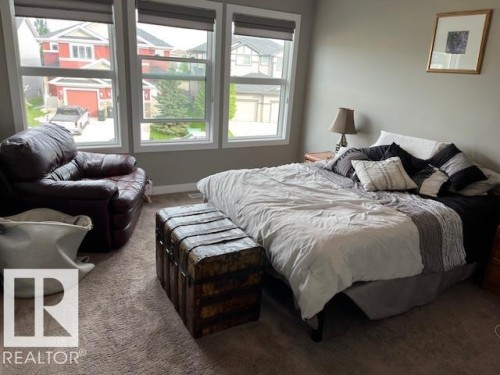 Bedroom featuring three large windows with roller shades, carpet flooring, and a neutral wall color - 138 Reed Place, Leduc, AB 