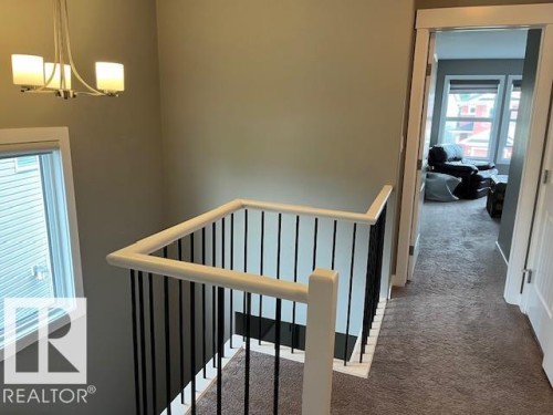 Staircase featuring white newel posts, white handrails, and black metal balusters - 138 Reed Place, Leduc, AB 