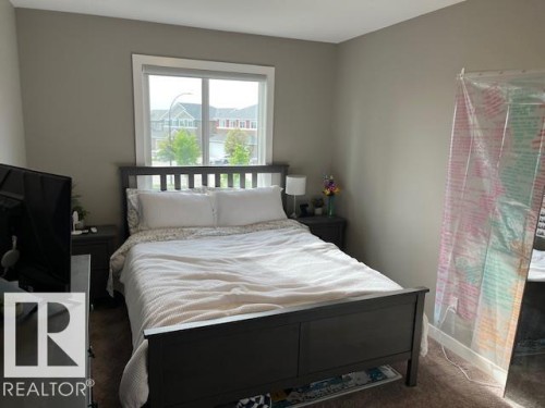 Bedroom featuring neutral wall paint, carpet flooring, and a large window with white trim - 138 Reed Place, Leduc, AB 