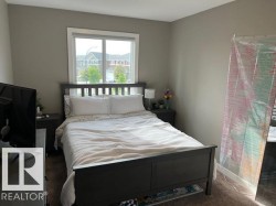 Bedroom featuring neutral wall paint, carpet flooring, and a large window with white trim - 