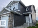 Contemporary exterior with dark horizontal siding, light stone accents, a single-car garage, and a covered front entry - 138 Reed Place, Leduc, AB 