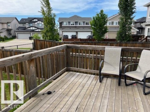 Outdoor wooden deck with slatted railing, overlooking a fenced backyard and residential street - 138 Reed Place, Leduc, AB 