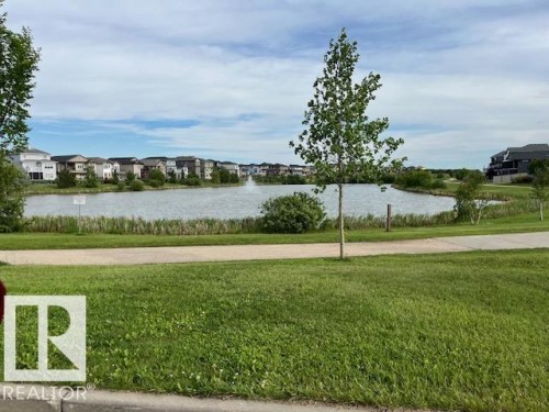 Expansive green space featuring a paved pathway and mature landscaping - 138 Reed Place, Leduc, AB 
