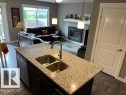 Kitchen island featuring a dual stainless steel sink and granite-style countertop - 138 Reed Place, Leduc, AB 