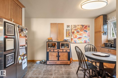 Kitchen featuring wood-finish cabinetry, stainless steel refrigerator, and recessed lighting - 12115 53 Street, Edmonton, AB 