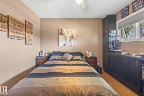 Bedroom featuring wood-finish flooring, a ceiling fan, and built-in dark cabinetry with ample storage - 12115 53 Street, Edmonton, AB 