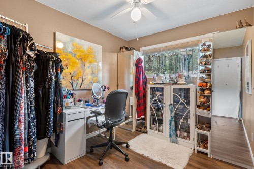 Interior room featuring wood-finish flooring, a window with exterior tree scenery, a ceiling fan with integrated lighting, and neutral wall tones - 12115 53 Street, Edmonton, AB 