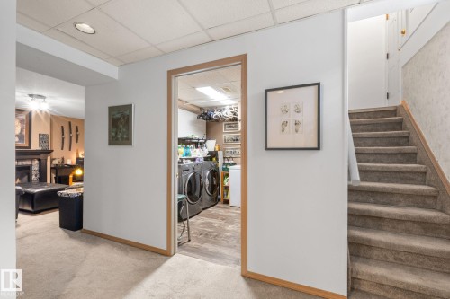 Dedicated laundry area featuring a washer and dryer, wood-finish flooring, and overhead lighting - 12115 53 Street, Edmonton, AB 