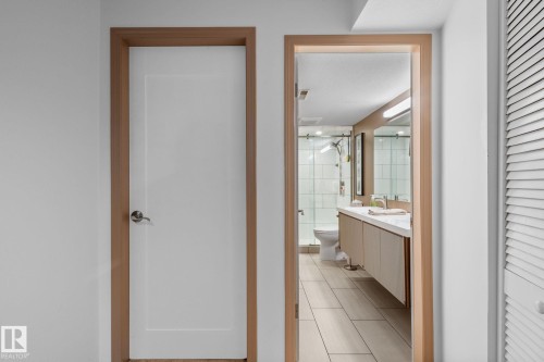 Bathroom entrance featuring a floating vanity with a light-colored countertop, dual undermount sinks, and a mirrored wall. Door to Bonus room - 12115 53 Street, Edmonton, AB 