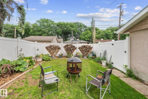 Private backyard with a manicured lawn, white privacy fencing, and a side access gate - 12115 53 Street, Edmonton, AB 