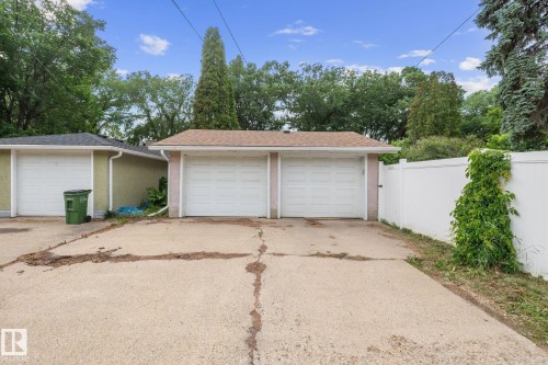 Two-car detached garage featuring dual white garage doors, a concrete driveway, and a light brown shingle roof - 12115 53 Street, Edmonton, AB 