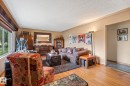 Bright living area featuring wood-finish flooring, a large window with natural light, and neutral wall tones - 12115 53 Street, Edmonton, AB 
