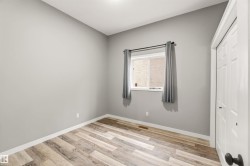 Neutral gray walls with white trim, wood-finish flooring, a window with a black rod, and a white bi-fold closet door - 