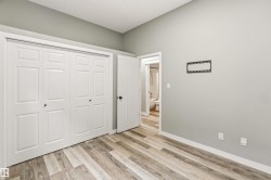 Room featuring wood-finish flooring, light gray walls, white baseboards, and a white six-panel bifold closet door - 