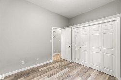 Spacious room featuring wood-finish flooring, light gray walls, and white baseboards - 