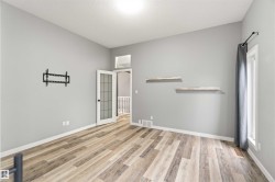 Spacious interior featuring wood-finish flooring, light gray wall paint, and white baseboards - 