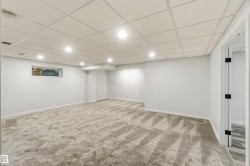 Spacious finished basement featuring recessed lighting, a drop ceiling, light gray walls, patterned carpeting, and a window - 