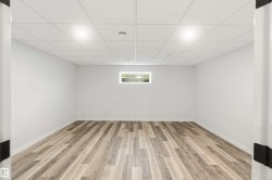 Spacious room featuring wood-finish flooring, crisp white walls, and a recessed window - 