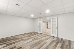 Spacious room featuring wood-finish flooring, light grey walls, and a white drop ceiling with recessed lighting - 