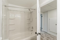 White bathtub and shower combination with integrated shelving, chrome fixtures, and a curved shower rod - 