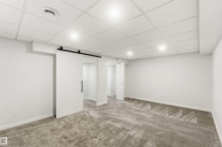 Spacious room featuring new carpeting, white walls, recessed lighting, and a modern barn door entry - 