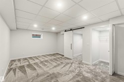 Spacious room featuring patterned gray carpeting, light gray walls, and recessed lighting in a grid ceiling - 