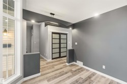 Contemporary interior with wood-finish flooring, recessed lighting, a decorative ceiling arch, and frosted glass sliding doors - 