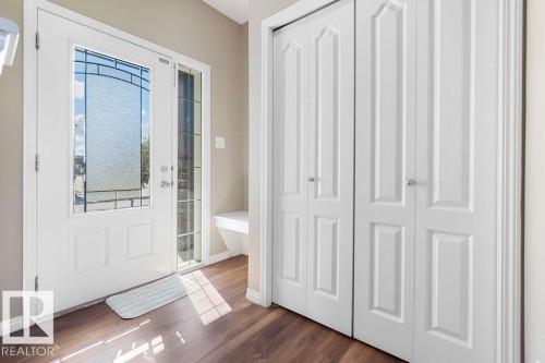 Entryway featuring a white door with decorative glass, a sidelight, and wood-finish flooring - 1306 32A Street, Edmonton, AB 