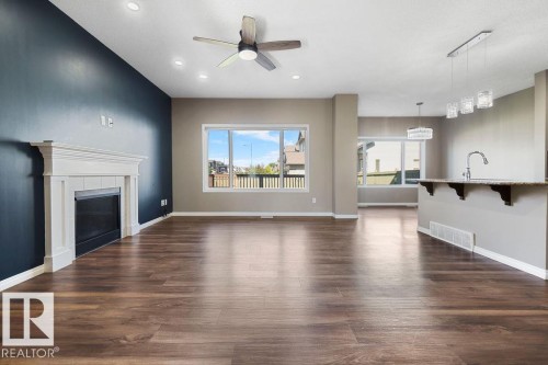 Open-concept living space featuring wood-finish flooring, a white mantel fireplace, recessed lighting, and a ceiling fan - 1306 32A Street, Edmonton, AB 