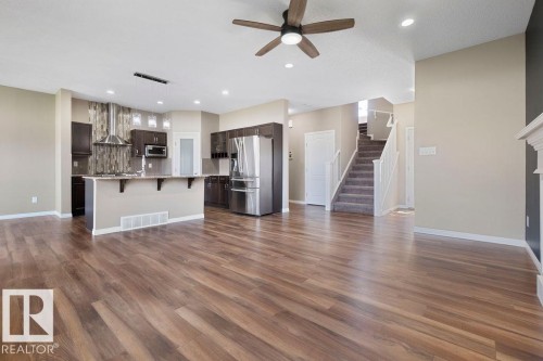 Spacious open-concept area featuring wood-finish flooring, a contemporary ceiling fan, and recessed lighting - 1306 32A Street, Edmonton, AB 