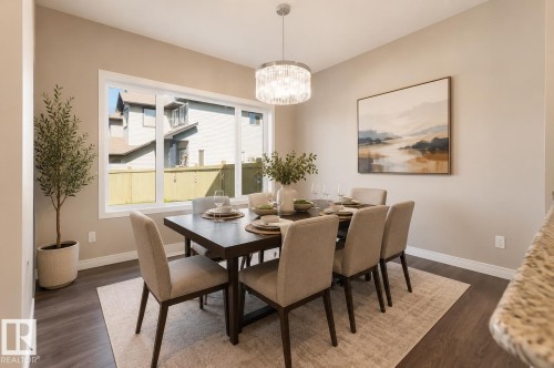 Dining area featuring a contemporary chandelier, large window with white trim, and dark wood-finish flooring - 1306 32A Street, Edmonton, AB 