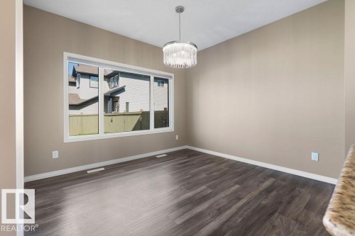 Recessed lighting, wood-finish flooring, and a modern chandelier illuminate this room - 1306 32A Street, Edmonton, AB 