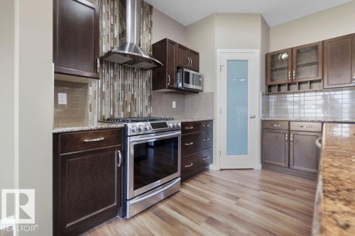 Contemporary kitchen featuring wood-finish flooring, dark wood cabinetry, and granite-style countertops - 1306 32A Street, Edmonton, AB 