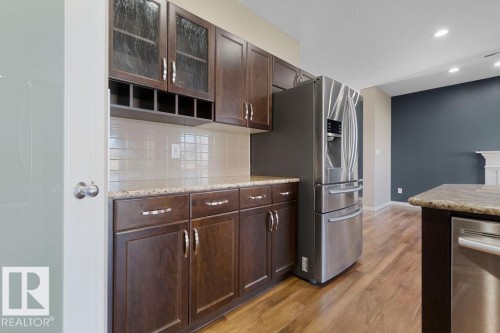 Kitchen featuring wood-finish flooring, dark wood cabinetry, and a stainless steel French door refrigerator - 1306 32A Street, Edmonton, AB 