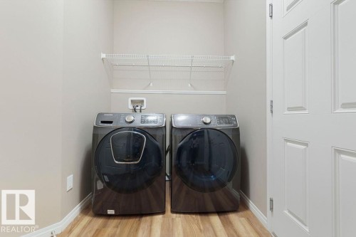 Dedicated laundry area featuring wood-finish flooring, light neutral wall paint, and a wire shelving unit - 1306 32A Street, Edmonton, AB 